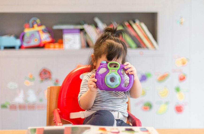girl holding purple and green camera toy