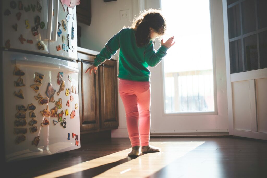 woman in red long sleeve shirt and pink pants standing near white top mount refrigerator