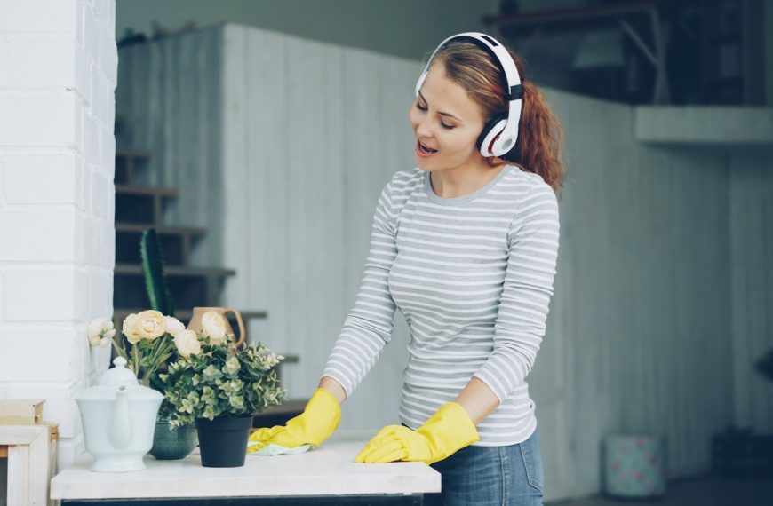 Woman with headphones cleaning and singing