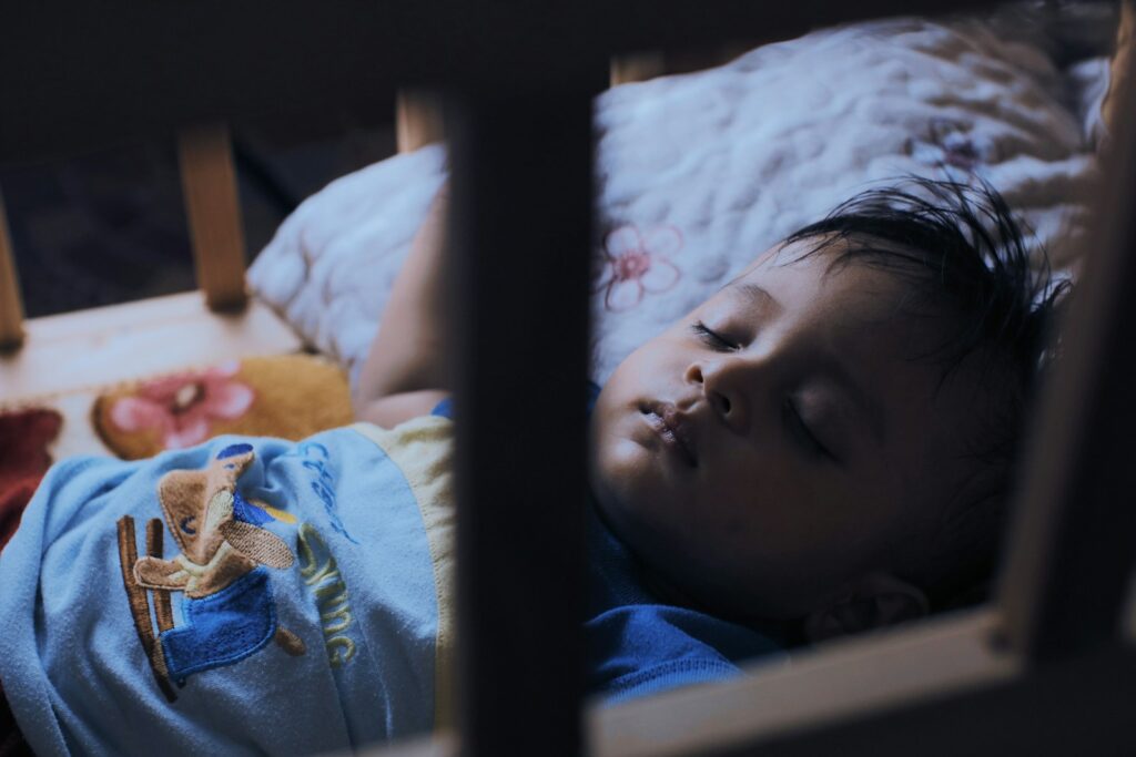 a young child sleeping in a crib with a stuffed animal