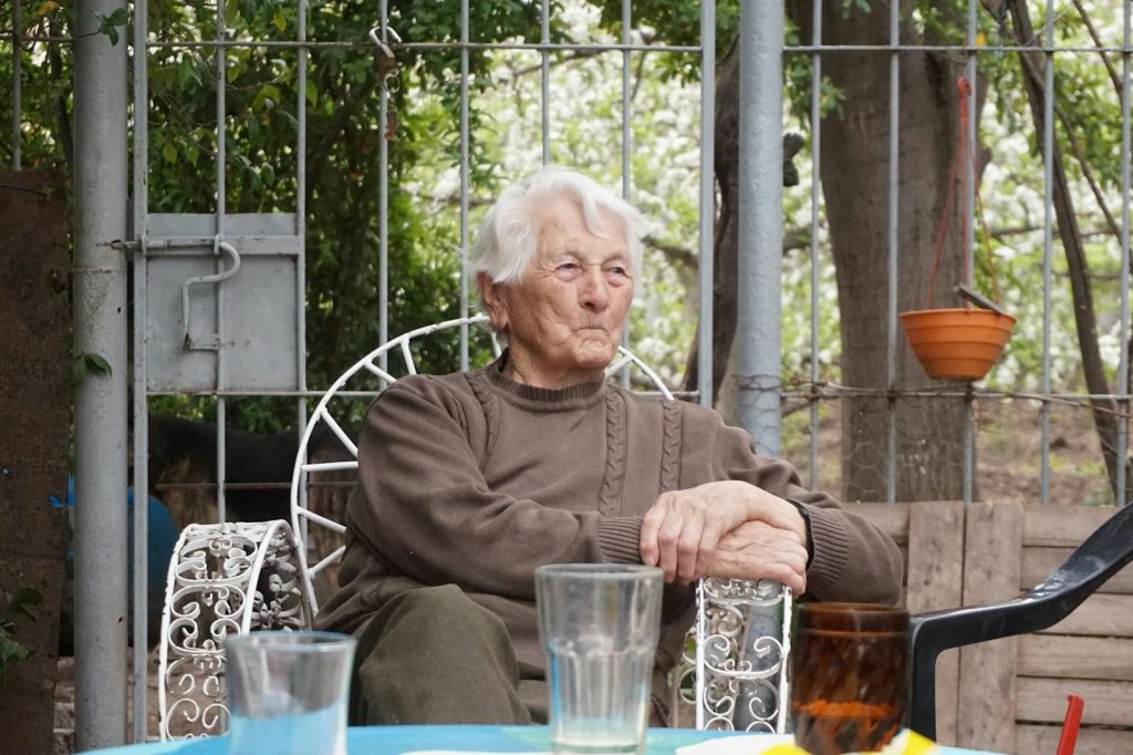 An elderly woman sits outside, relaxing.