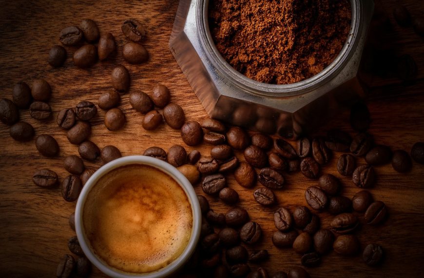 brown coffee beans beside white ceramic mug