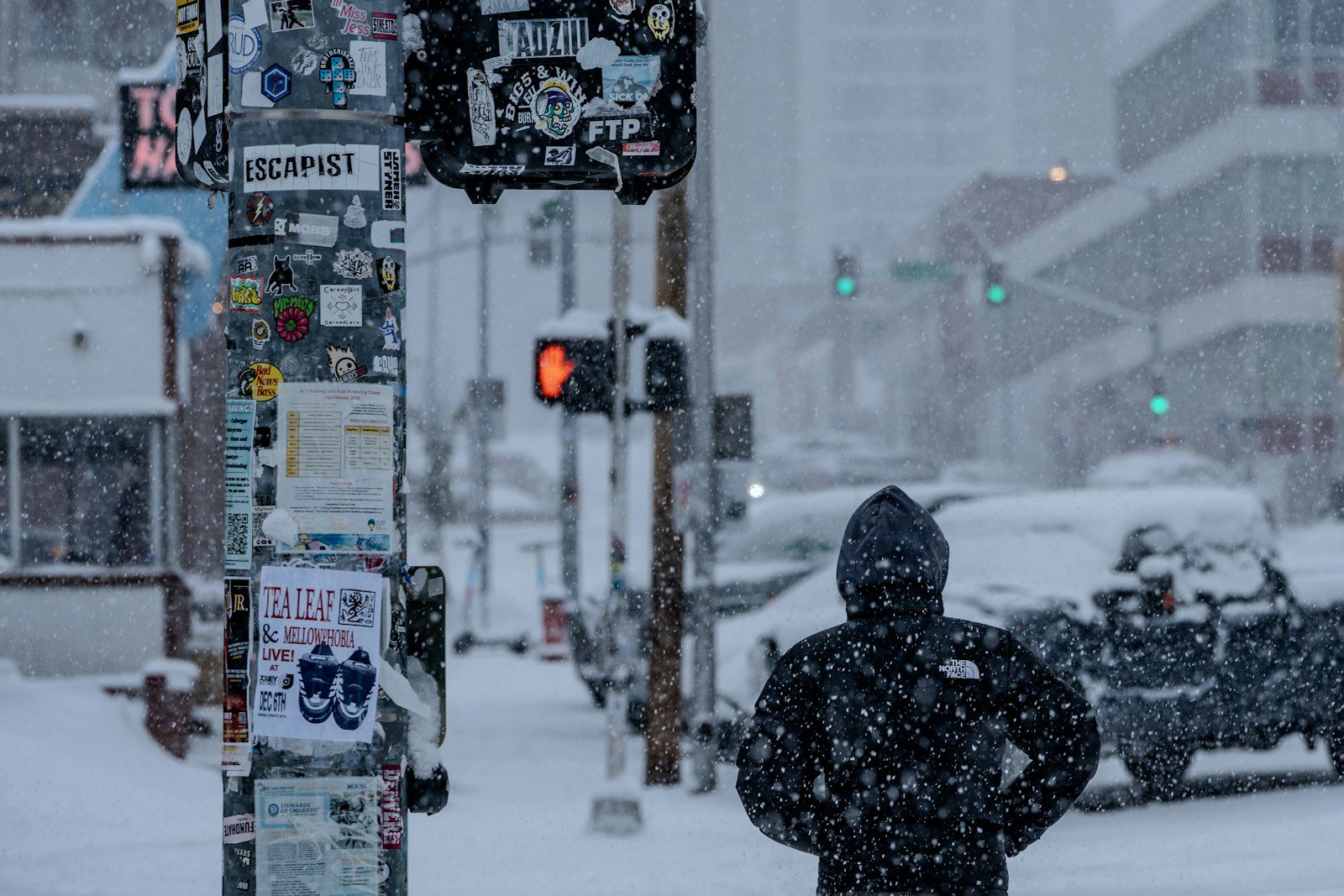 A person standing on a street corner in the snow