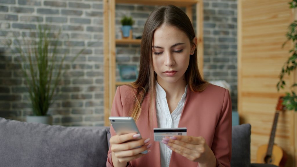 Young woman holding credit card and smartphone