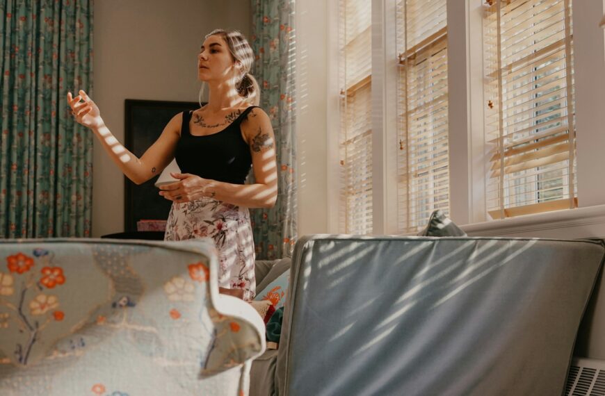 a woman standing in a living room holding a remote
