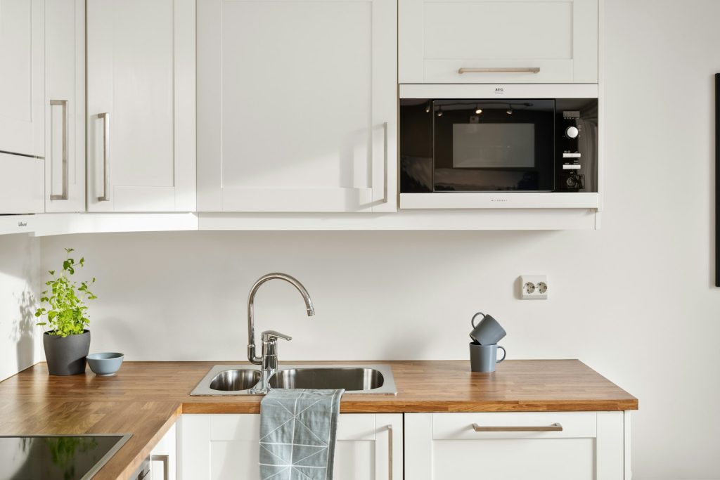 A kitchen with white cabinets and a wooden counter