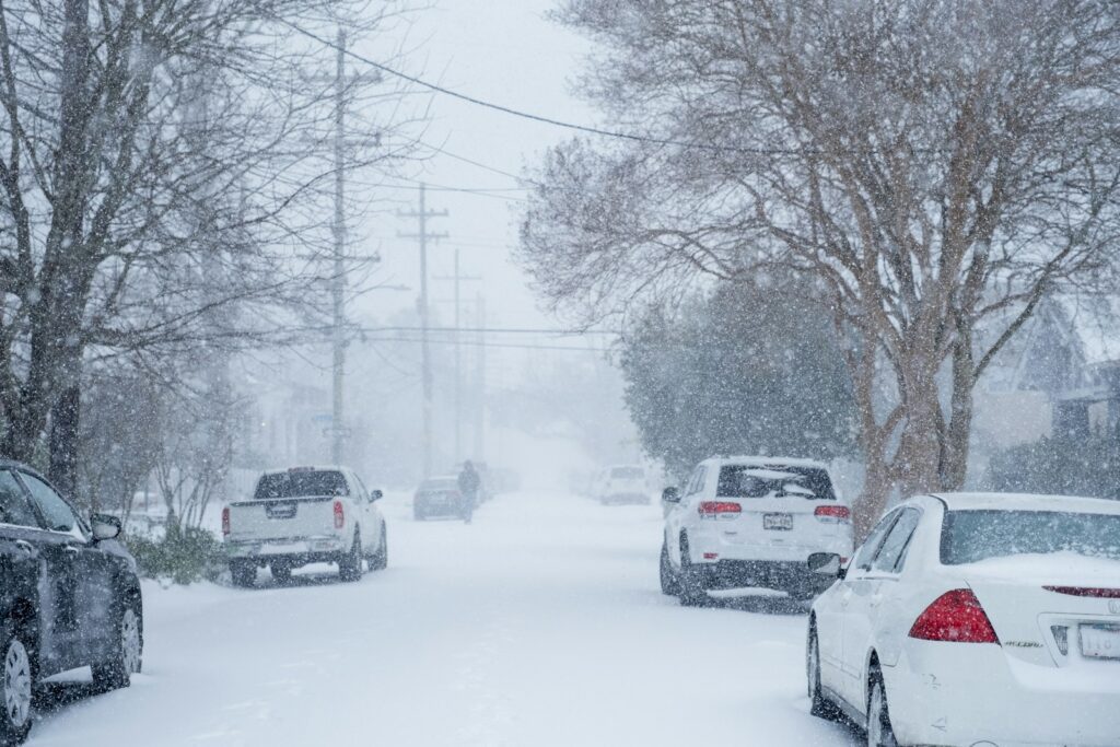 Several cars are parked on a snowy street