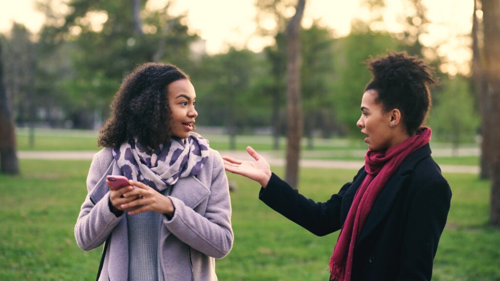 Two women talking in a park at sunset.