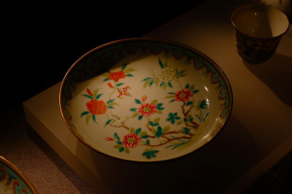 A decorated porcelain plate displayed under dramatic lighting.