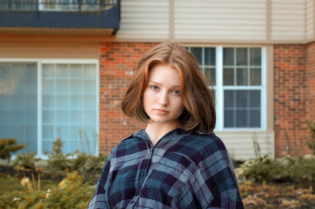 woman in blue and gray plaid top beside concrete structure