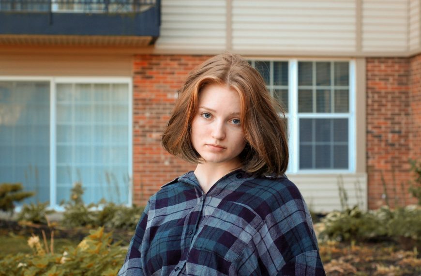 woman in blue and gray plaid top beside concrete structure