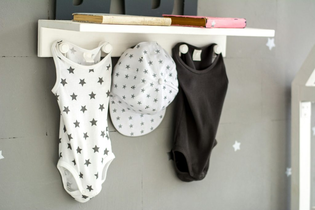 a baby's bodysuit and hat hanging on a wall