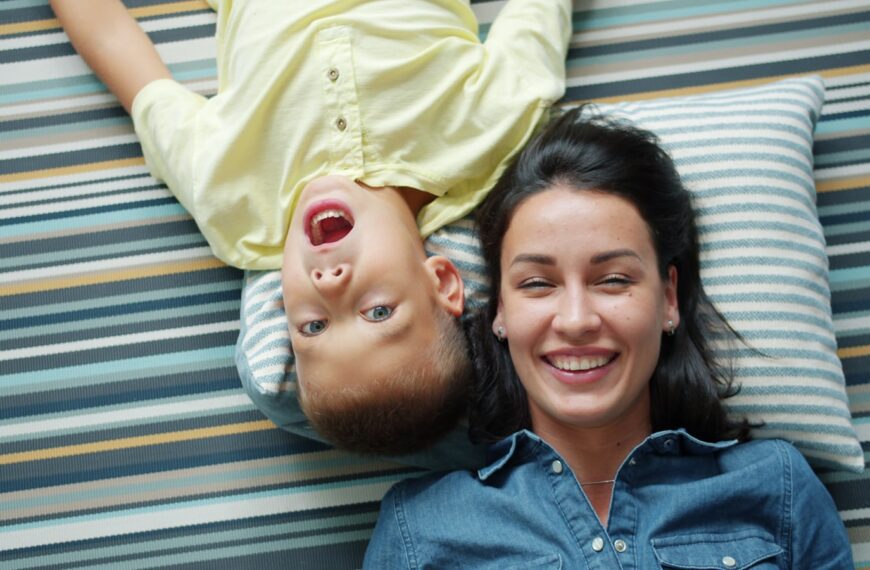 Mother and son lying on striped rug smiling