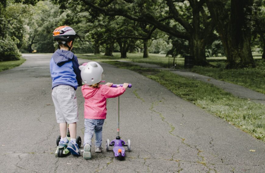 two toddler's walking on road near green tree