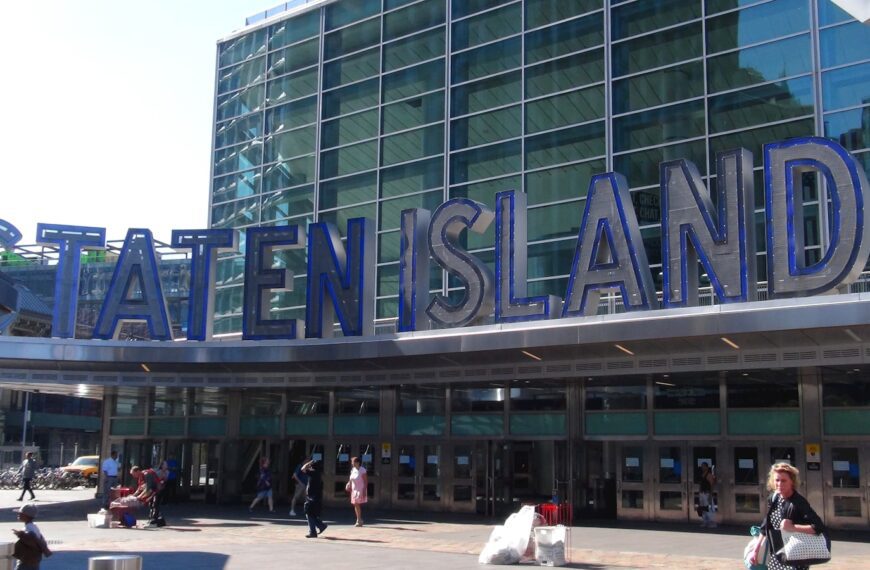 a large building with a sign on it with Staten Island Ferry in the background
