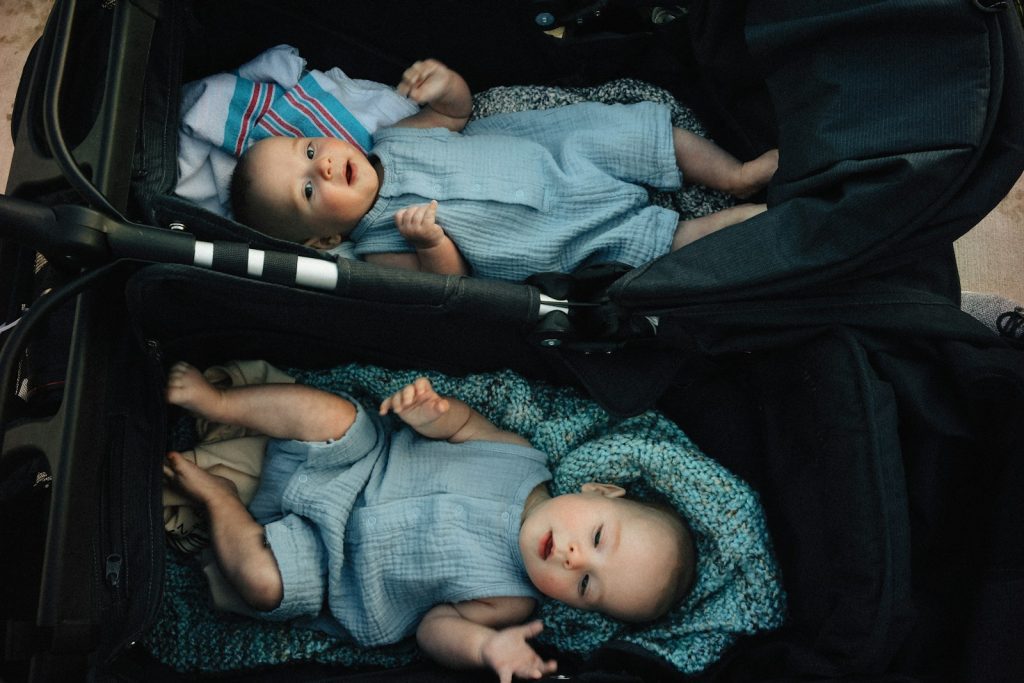 Two babies relaxing in their stroller.