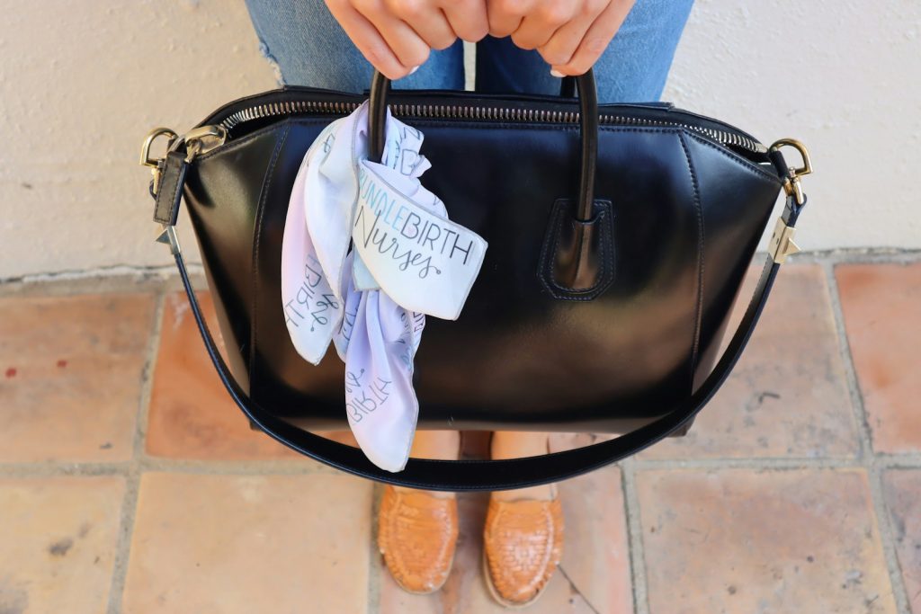 a woman holding a black purse with a white ribbon on it