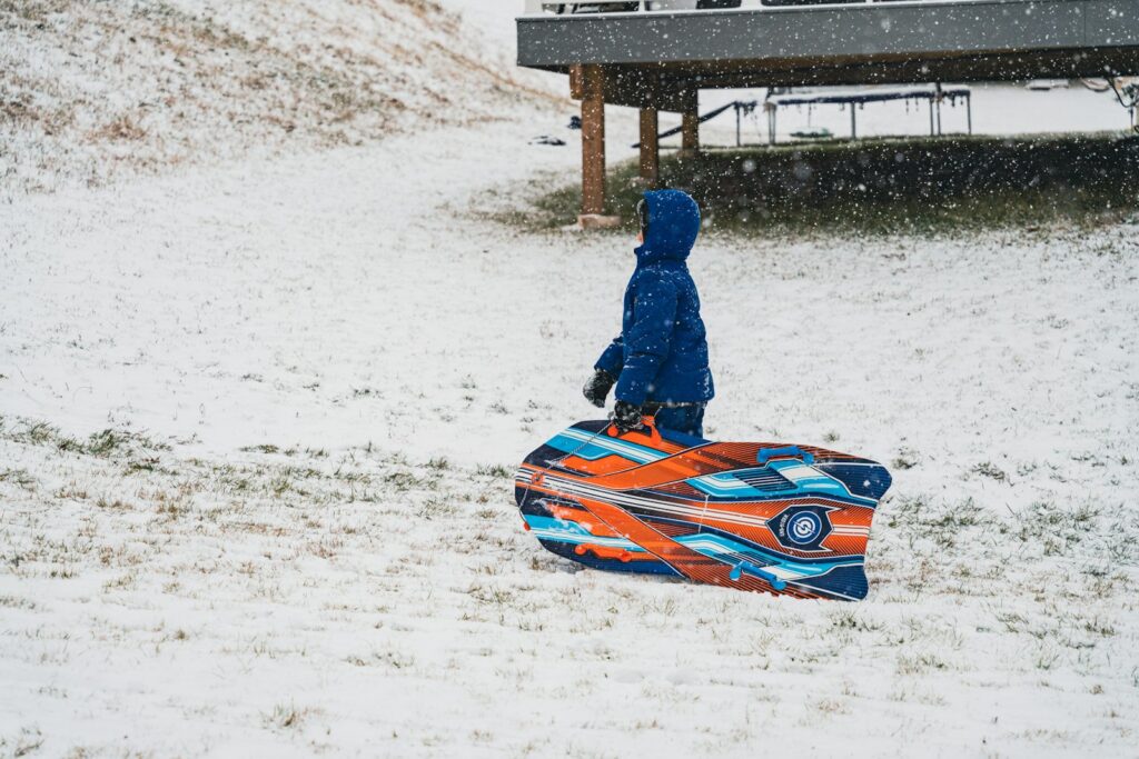 a person walking in the snow carrying a snowboard