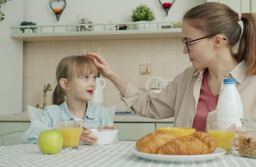 Mother touches daughter's hair during breakfast.