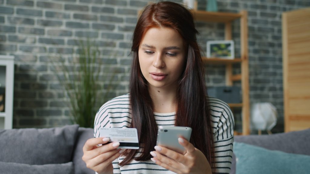 Woman holding credit card and smartphone for online shopping.