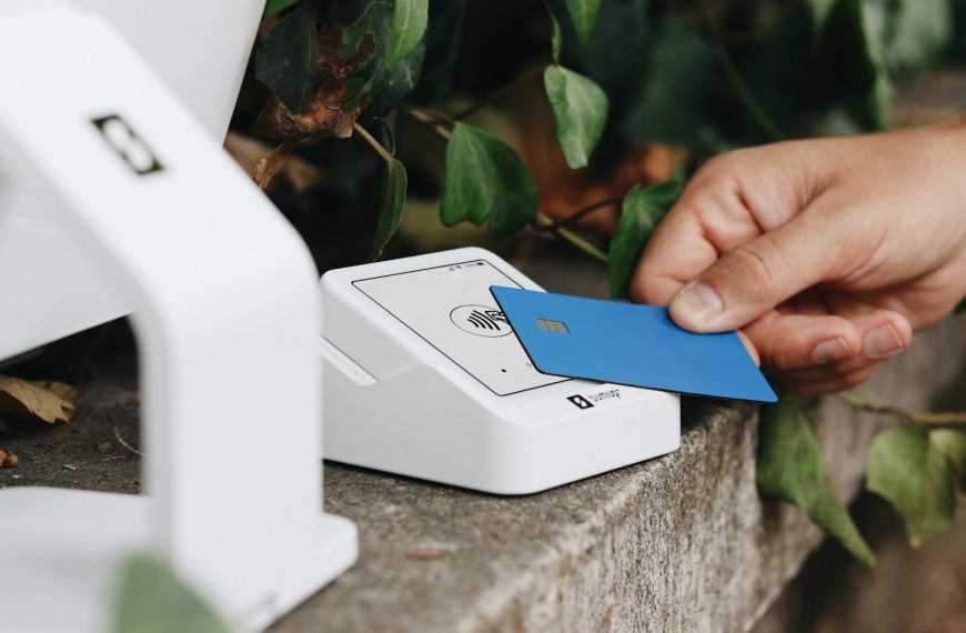 A person holding a credit card next to a machine
