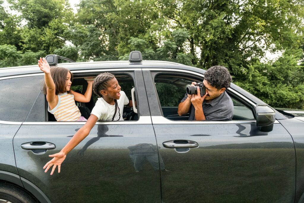Man photographs children leaning out of car window