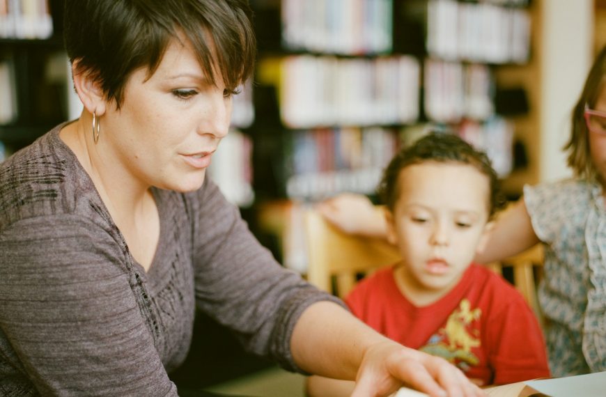 woman in gray long sleeve shirt sitting beside boy in orange crew neck shirt