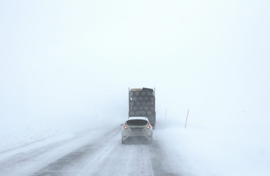 white car behind a truck on snowy road