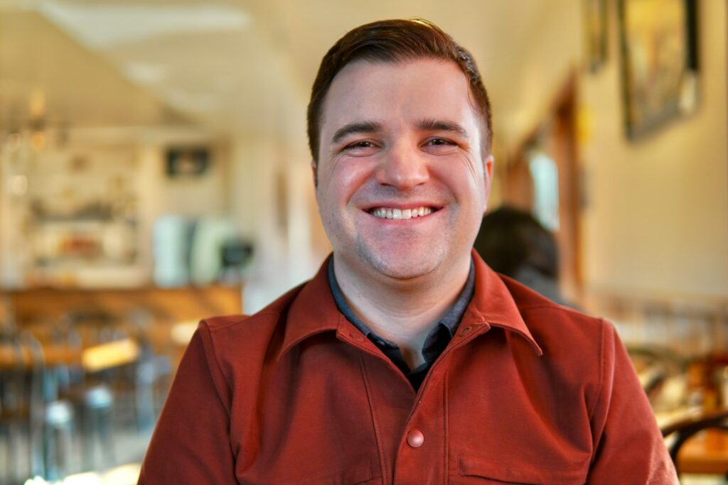 A man in a red shirt smiling at the camera