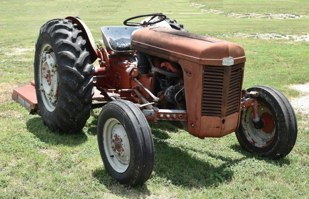 an old red tractor parked in a field