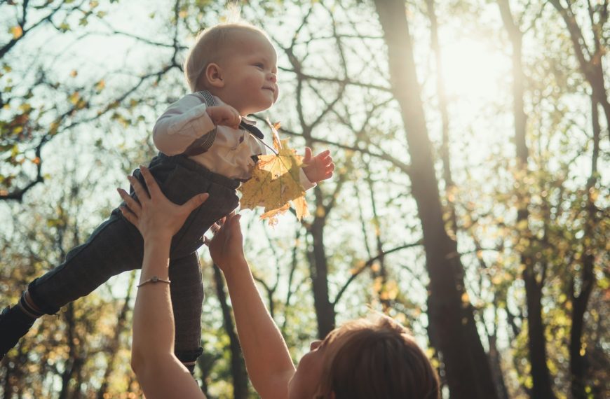 close-up photography of woman carrying a baby near outdoor during daytime