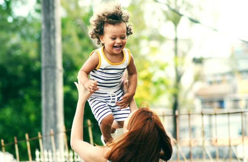 selective focus photo of woman lifting child during daytime