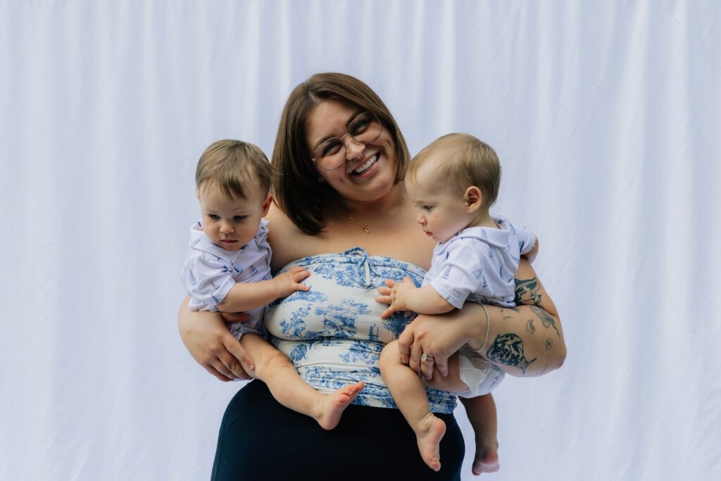 Woman holding two babies in front of white backdrop