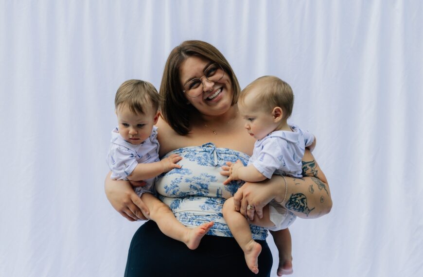 Woman holding two babies in front of white backdrop