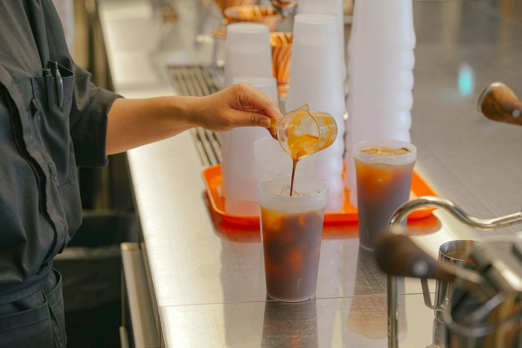 a person pouring a drink into a glass