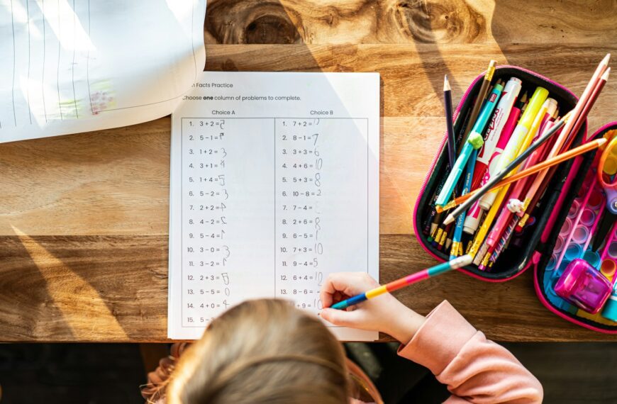 A little girl sitting at a table with a bag of pencils