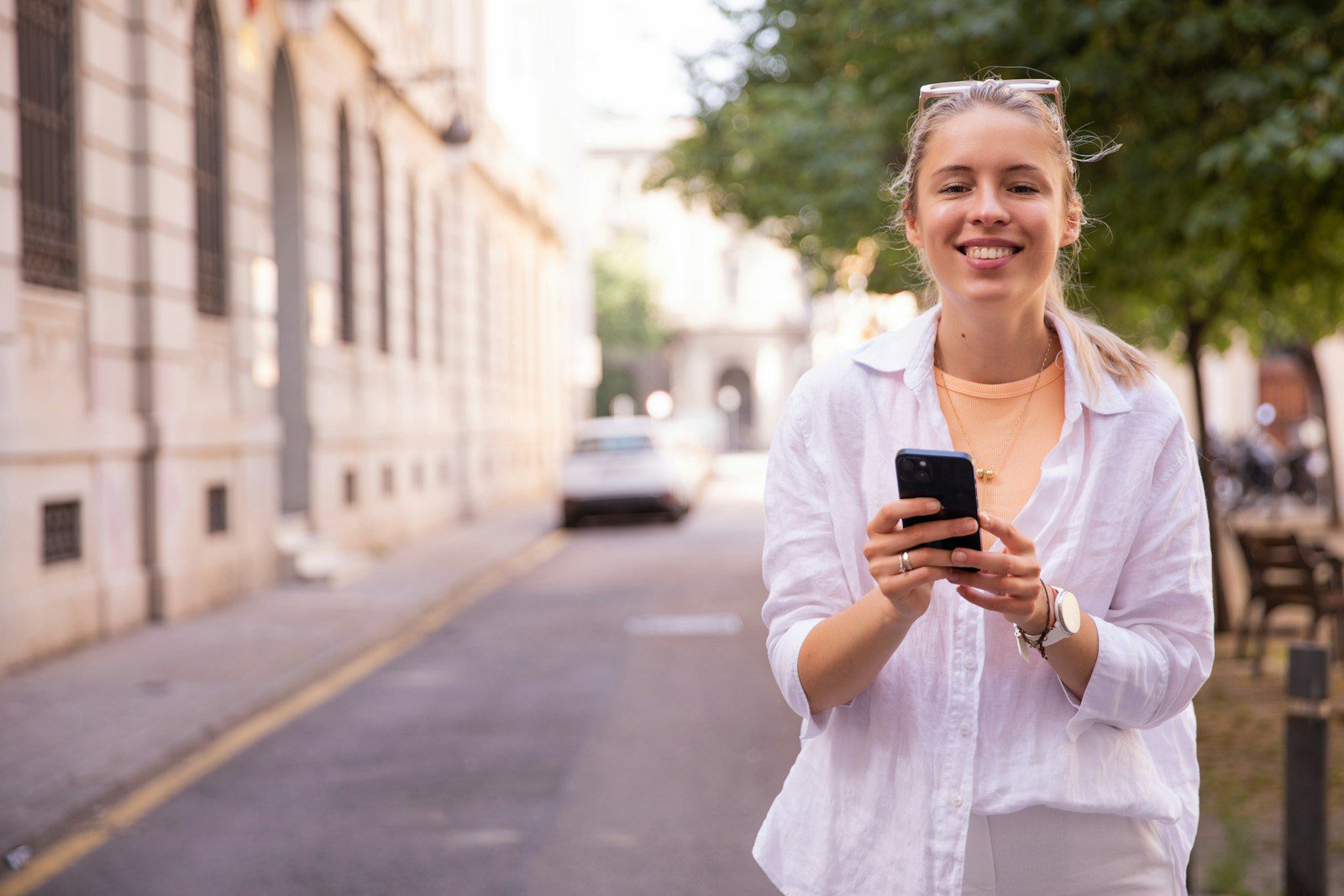 a woman standing on a street holding a cell phone