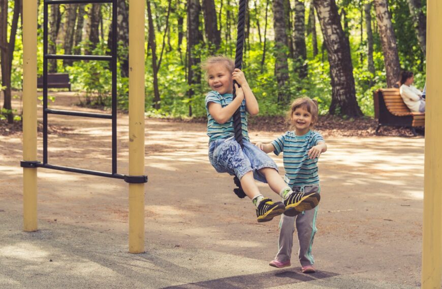 2 boys sitting on swing during daytime