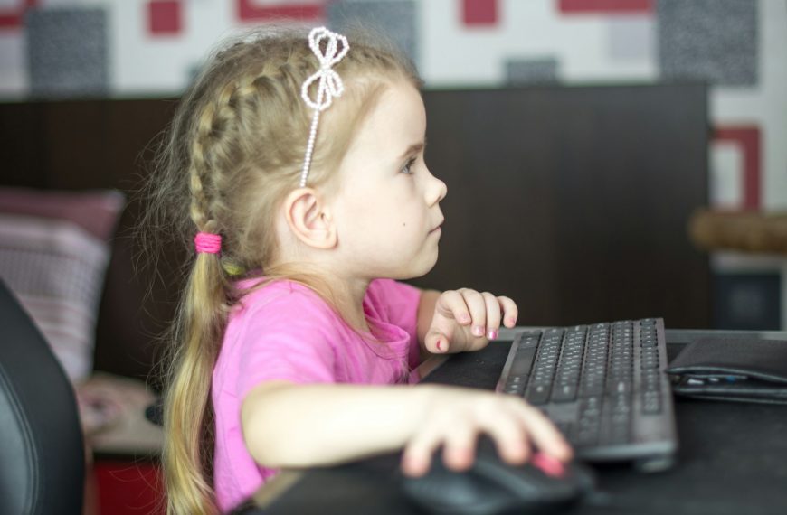 a little girl sitting in front of a computer keyboard