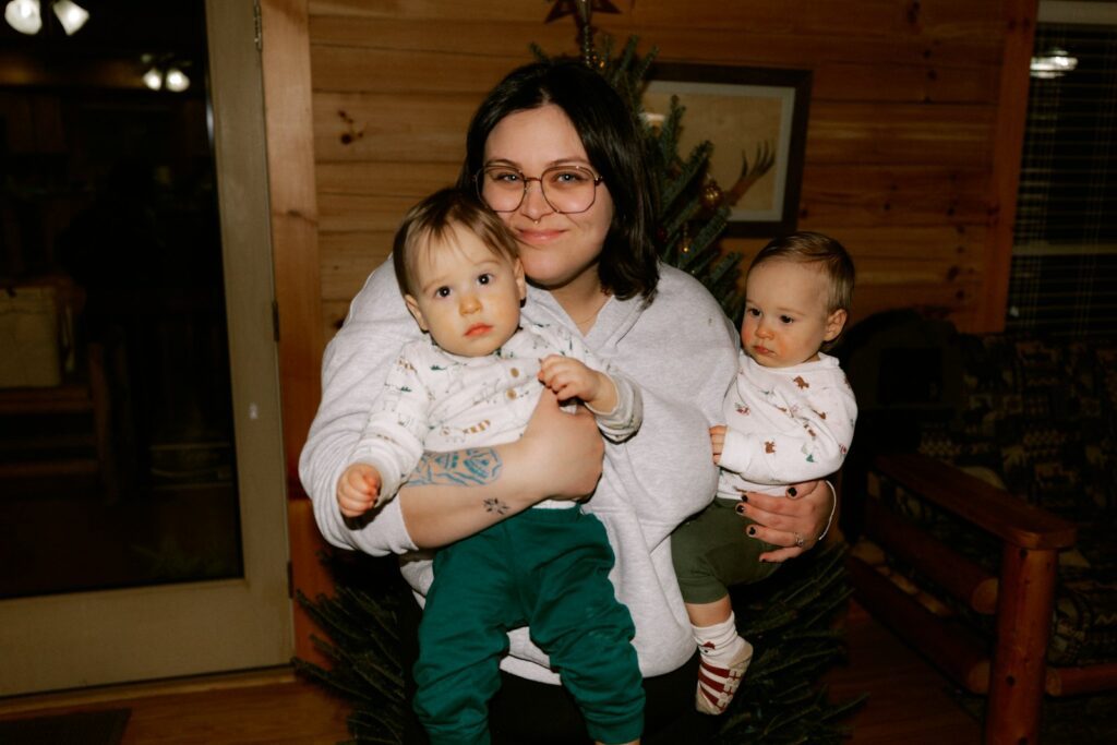Woman holding two babies in a room
