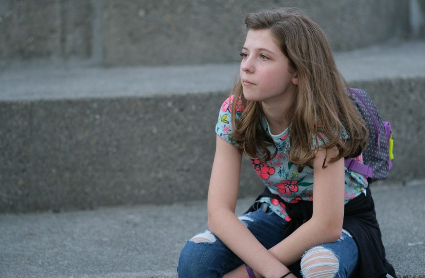 A young girl sitting on steps with a backpack on