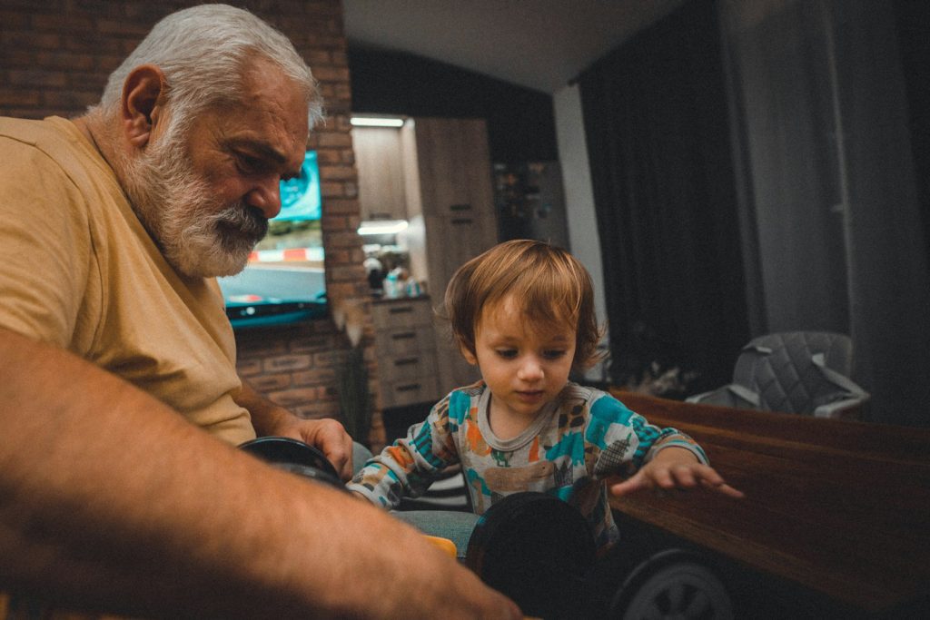 an older man and a young boy playing with a toy car