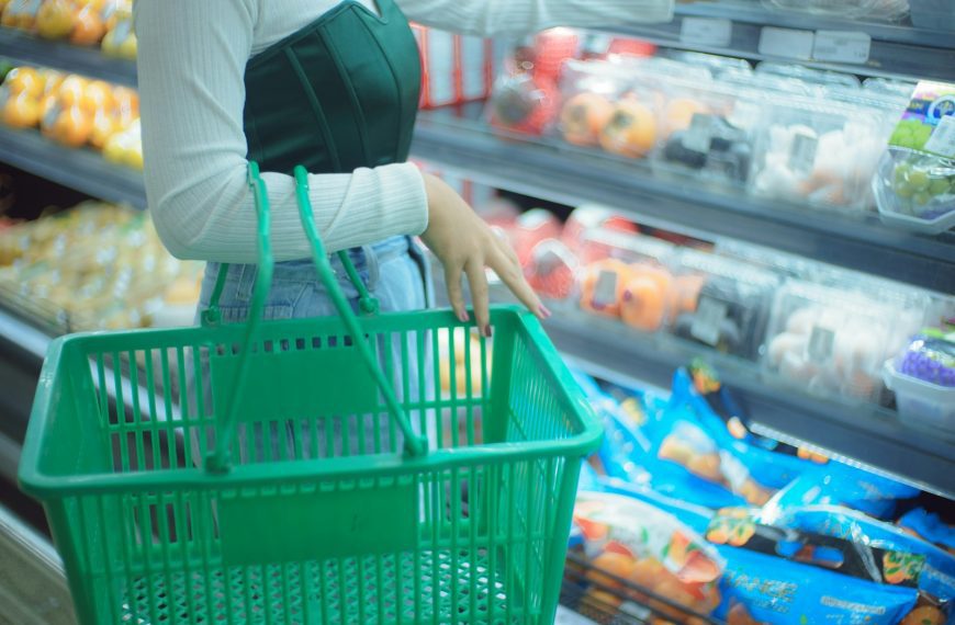 a woman holding a shopping basket in a grocery store