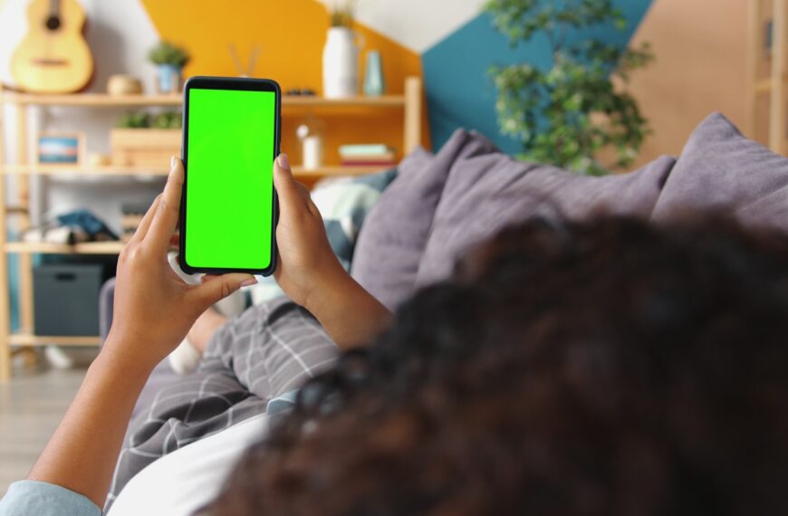 Person holding a smartphone with a green screen.