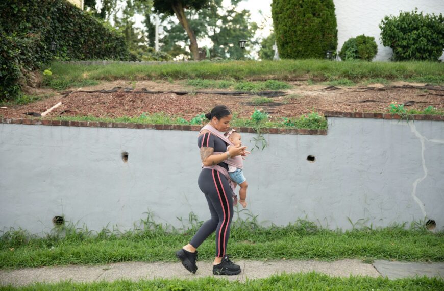 a person holding a baby by a pond
