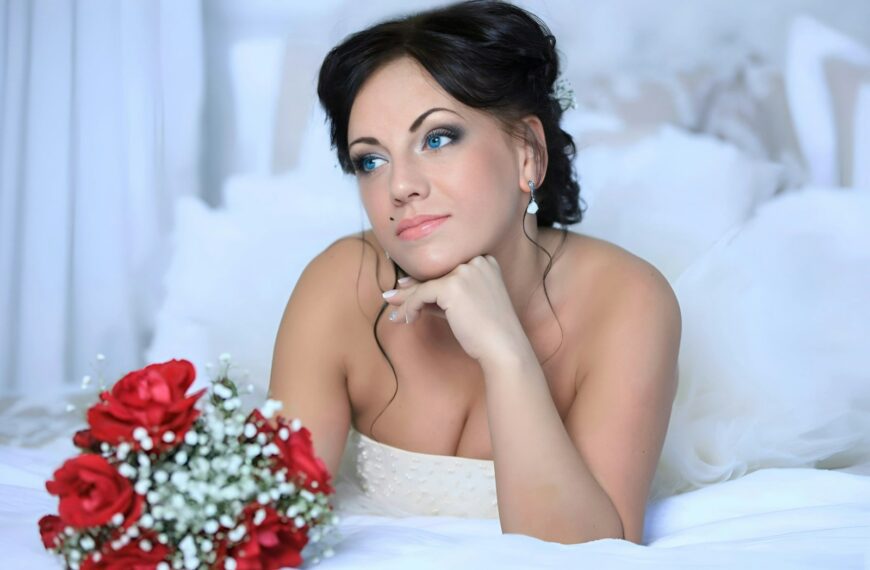 a woman laying on top of a bed next to a bouquet of flowers