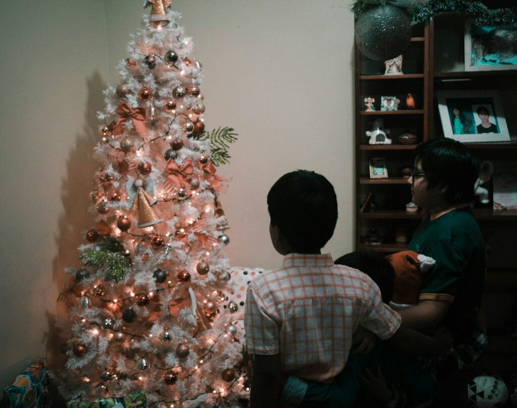 man in white and red plaid dress shirt standing beside christmas tree