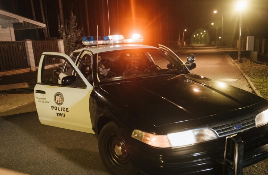 Police car with flashing lights parked at night during an urban patrol.
