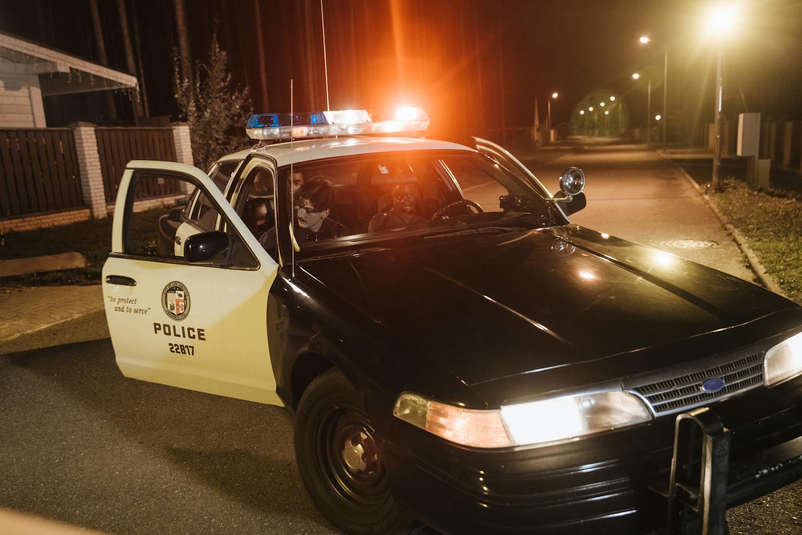 Police car with flashing lights parked at night during an urban patrol.