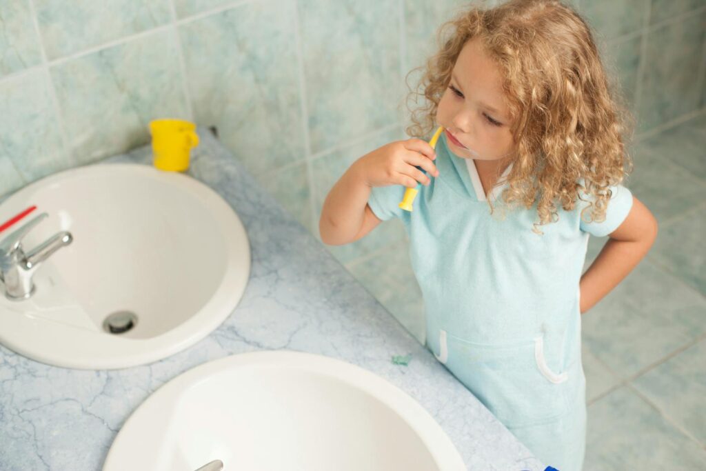 Child brushing teeth by sink, highlighting personal hygiene habits.